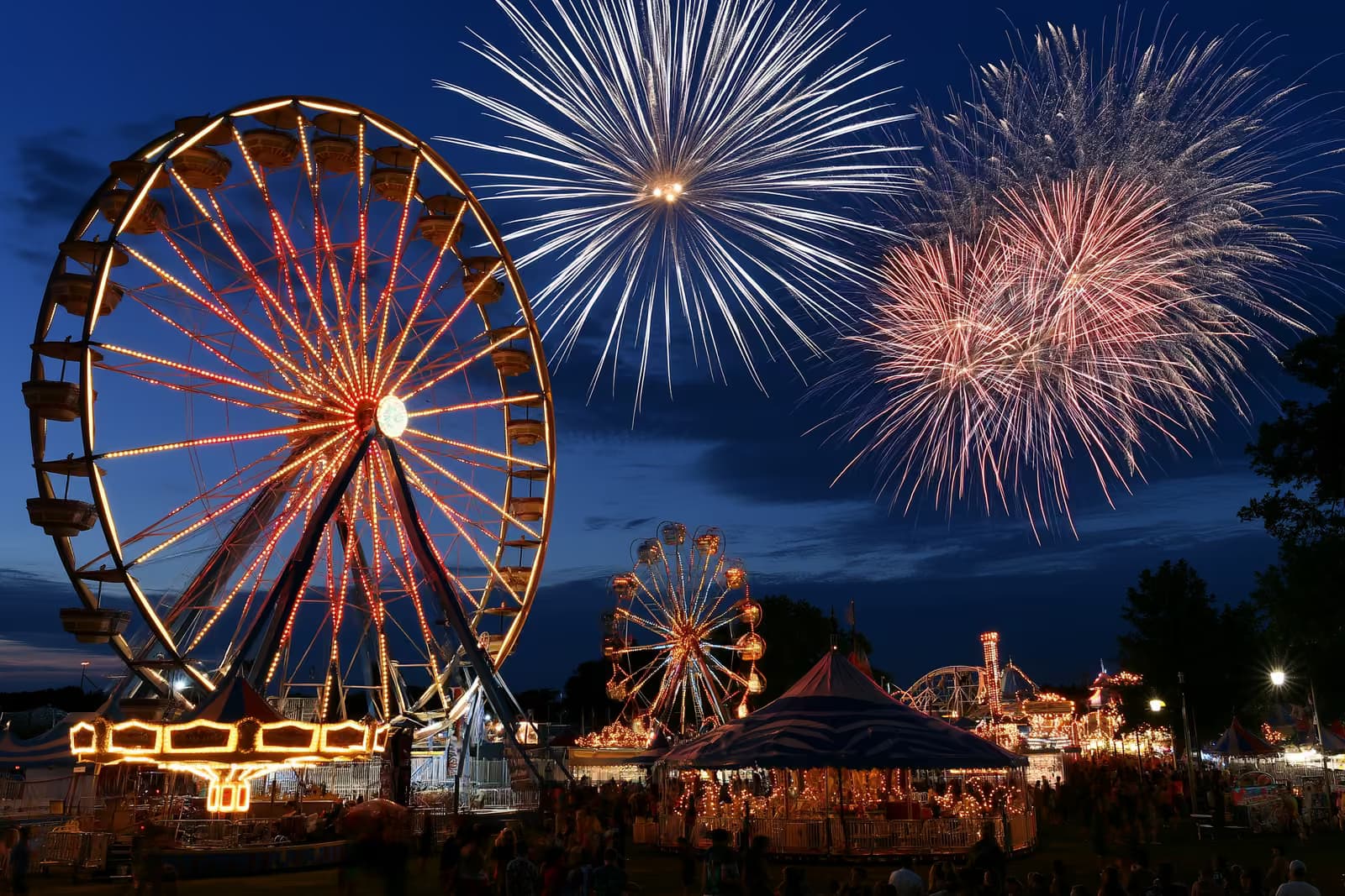 Hamburg'daki Heiligengeistfeld'de gün batımında büyük bir dönme dolap ve çeşitli eğlence araçlarıyla ışıl ışıl aydınlatılmış bir lunapark.