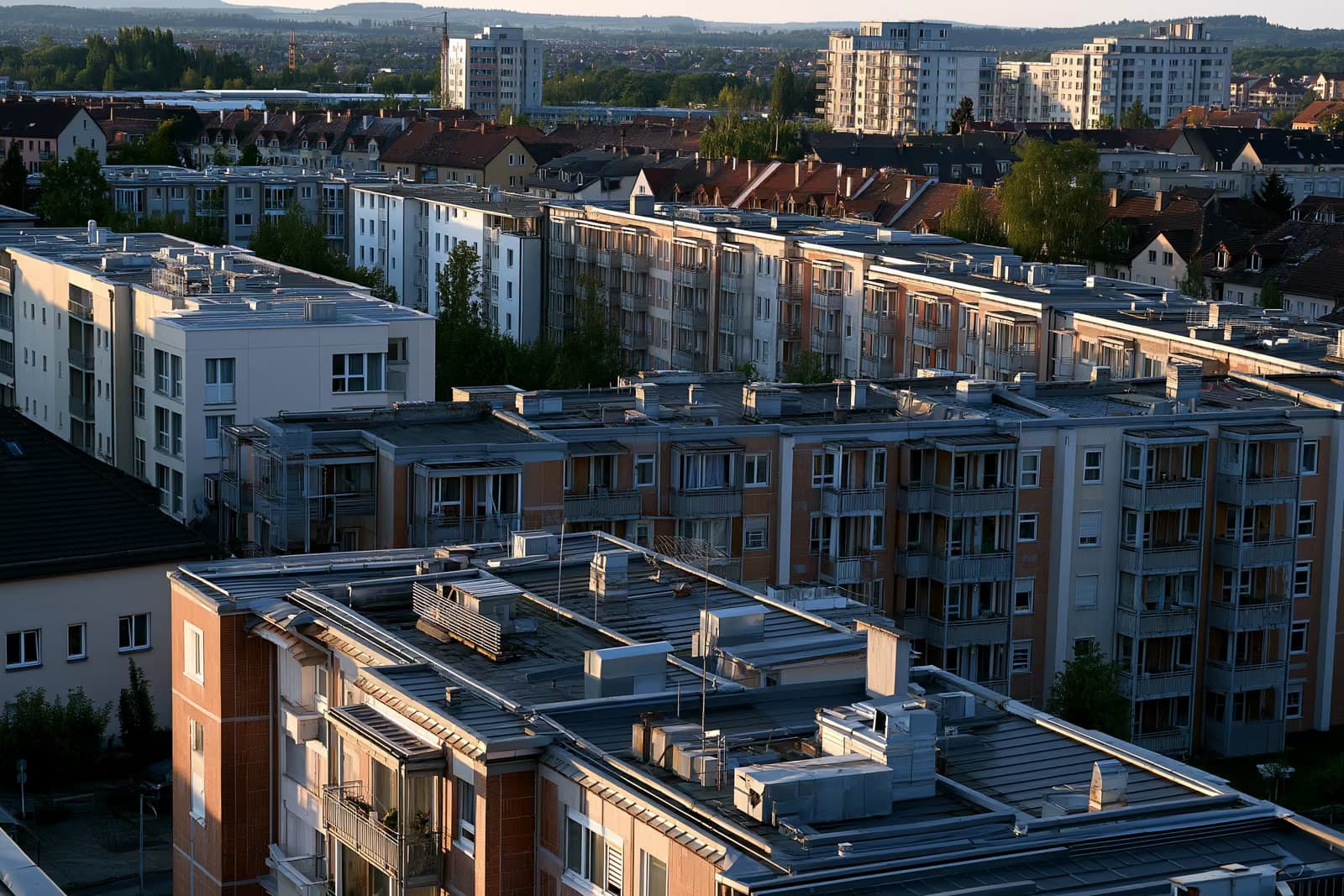 Almanya'da bir şehirdeki apartman binalarının çatıları ve ısıtma menfezleri, sıcak öğleden sonra ışığı altında.