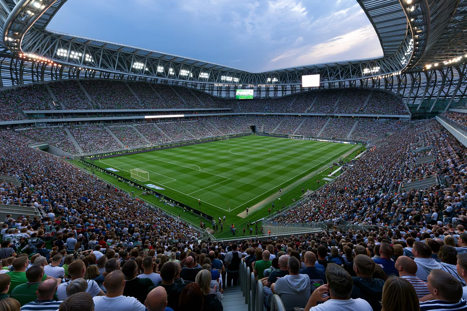 Yaz akşamında projektörler altında taraftarlarla dolu büyük bir futbol stadyumu.